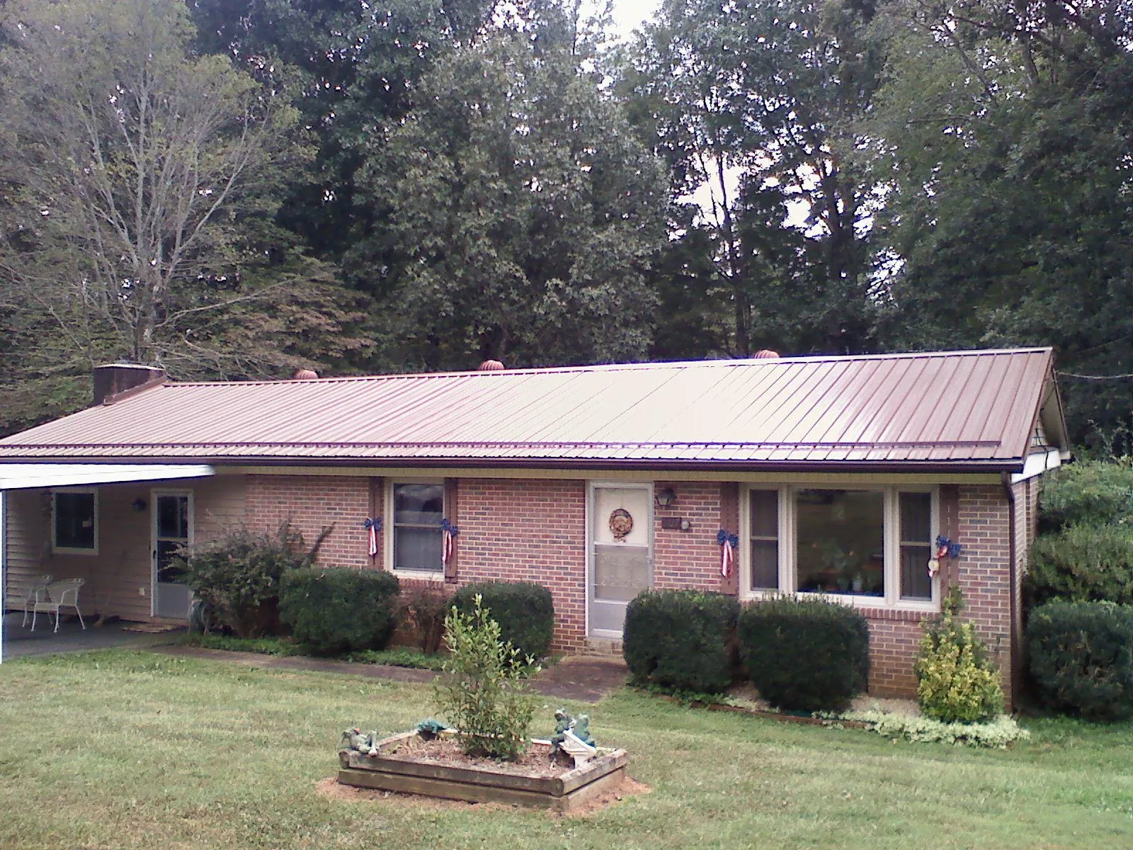 Bronze metal roof on a brick ranch home with a carport in Wilson